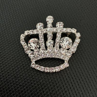 Sale Photo Thumbnail #181: A sparkling crown-shaped brooch featuring round and marquise-cut clear rhinestones set in silver-tone metal. Good condition with all stones intact and a secure pin back mechanism.