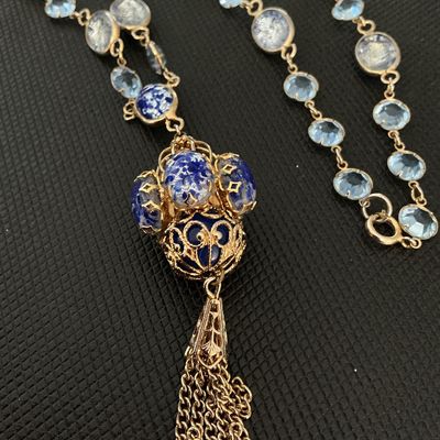 Sale Photo Thumbnail #152: Ornate vintage costume necklace featuring blue and silver foil art glass beads, light blue bezel-set crystals, and a detailed cage-style pendant with hanging chain tassel. Gold-tone chain settings with spring ring clasp closure. Excellent vintage conditio