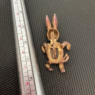 Sale Photo Thumbnail #228: Vintage gold-tone textured metal brooch featuring a playful bunny rabbit design. The body is set with an oval tiger's eye cabochon, and the head features red rhinestone eyes and nose details. Standard pin back closure with pin mechanism. Shows light vinta
