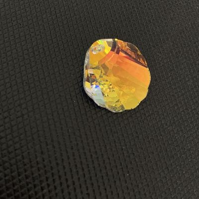 Sale Photo Thumbnail #168: Faceted crystal ornament or chandelier prism crafted in a scallop shell shape with an iridescent, aurora borealis-style golden finish. Features a single drilled hole at the top for hanging or jewelry making. Appears to be in good condition with no visible