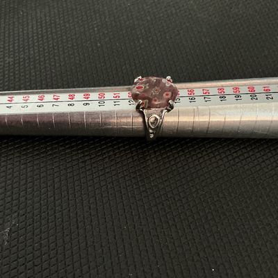 Sale Photo Thumbnail #205: A silver-tone ring featuring a bezel/prong-set oval millefiori glass cabochon with red, green, and white floral design elements inside a pinkish glass base. Shows minor surface wear consistent with age. Size measures approximately 6.5 - 6.75 on a ring man