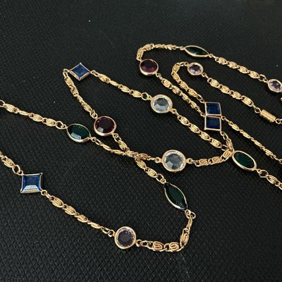 Sale Photo Thumbnail #165: A vintage-style long gold-tone chain necklace featuring bezel-set multi-colored glass jewels in various shapes including round, square/diamond, marquise, and oval. Colors include deep red/purple, blue, green, and clear/lavender. Good overall condition wit