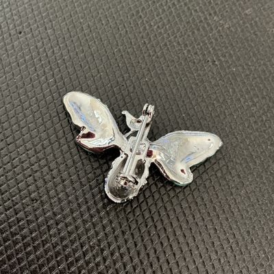 Sale Photo Thumbnail #219: A detailed bee brooch featuring silver-tone metal construction, light green enamel wing details, green rhinestones on the head, and pink rhinestone eyes. Black enamel striping decorates the body. Includes a standard pin back clasp mechanism. Appears in go