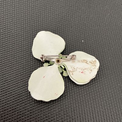 Sale Photo Thumbnail #174: Vintage light green/chartreuse enamel flower brooch pin featuring three large petals and detailed center stamen. Back side shows a standard pin stem and clasp mechanisms along with light wear and paint loss to the reverse finish. Measures approximately 2.