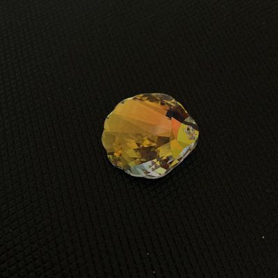 Sale Photo Thumbnail #169: Faceted crystal ornament or chandelier prism crafted in a scallop shell shape with an iridescent, aurora borealis-style golden finish. Features a single drilled hole at the top for hanging or jewelry making. Appears to be in good condition with no visible
