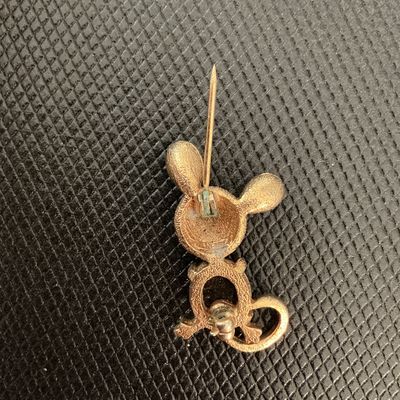 Sale Photo Thumbnail #225: Charming vintage gold-tone mouse brooch featuring a textured head, black cabochon stone body, small black eye detail, and a curved tail. C-clasp fastener on the back shows minor verdigris/patina near the pin stem hinge, otherwise in good condition with li