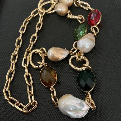 Sale Photo Thumbnail #137: Gold-tone chain station necklace featuring large, irregularly shaped baroque pearls interspersed with faceted oval crystals in red, green, amber, and dark green. The necklace combines a paperclip link chain with textured circular accent links. Good pre-ow