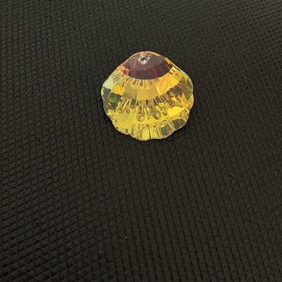 Sale Photo Thumbnail #167: Faceted crystal ornament or chandelier prism crafted in a scallop shell shape with an iridescent, aurora borealis-style golden finish. Features a single drilled hole at the top for hanging or jewelry making. Appears to be in good condition with no visible