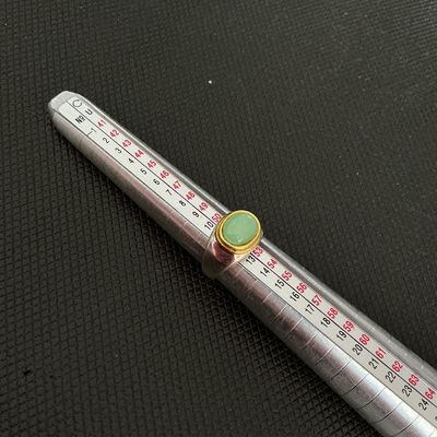 Sale Photo Thumbnail #212: A stylish ring featuring a smooth, oval-shaped light green stone cabochon set in a gold-tone bezel over a textured silver-tone band. Ring mandrel photos show a size of approximately 6. Light surface wear consistent with previous use.