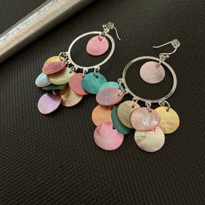 Sale Photo Thumbnail #143: Pair of silver-tone hoop chandelier dangle earrings featuring colorful, iridescent mother of pearl shell discs in shades of pink, teal, yellow, and orange. Fitted with fishhook backs and plastic stoppers. In good pre-owned condition with no visible damage