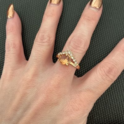 Sale Photo Thumbnail #233: Gold-tone costume ring featuring a faceted light orange/champagne round center stone set above a chevron band lined with clear rhinestones. Ring measures approximately size 8.5 to 8.75 on a ring sizer mandrel. Good pre-owned condition with light surface w