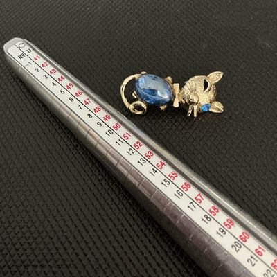 Sale Photo Thumbnail #202: A charming vintage gold-tone cat brooch featuring a textured finish, a bright blue cabochon body, and a blue rhinestone eye. Measures approximately 1.5 inches in length. In good vintage condition with minor wear consistent with age. Pin back fastener is f