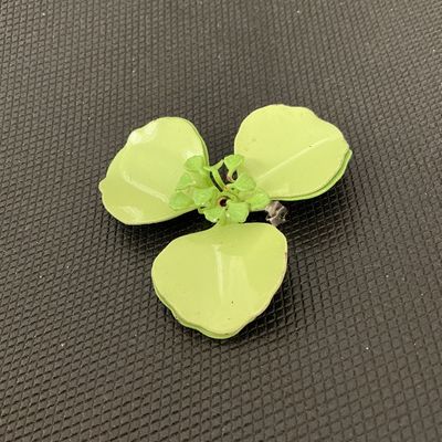Sale Photo Thumbnail #173: Vintage light green/chartreuse enamel flower brooch pin featuring three large petals and detailed center stamen. Back side shows a standard pin stem and clasp mechanisms along with light wear and paint loss to the reverse finish. Measures approximately 2.