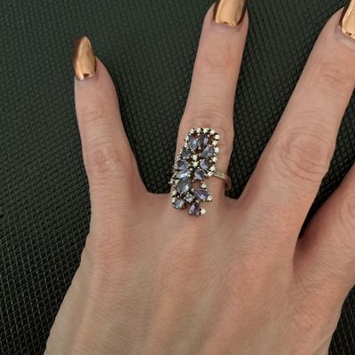 Sale Photo Thumbnail #207: An ornate, elongated statement ring featuring a cluster of pear-cut and round light purple stones (possibly tanzanite or iolite) accented with small clear accent stones. The ring band appears to be stamped 925 on the inner surface. Measured on a ring mand