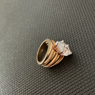 Sale Photo Thumbnail #146: Gold-tone fashion statement ring featuring a large marquise-cut clear stone set in a six-prong setting atop a split multi-band design. Shown on ring mandrel at approximately US size 5.5. Good pre-owned condition with light surface wear visible on the band