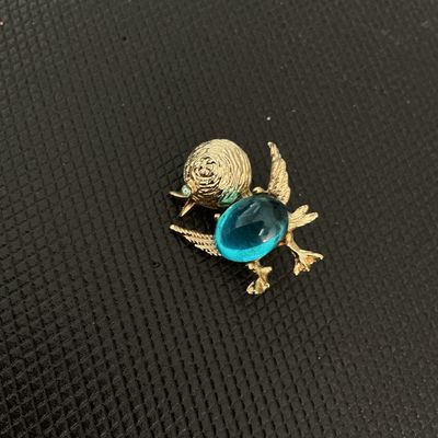 Sale Photo Thumbnail #187: Vintage Gerry's gold-tone bird or duck brooch featuring a bright blue jelly/cabochon belly and a small rhinestone eye. Textured finish on the head and wings with a rollover safety clasp on the back. Stamped Gerry's on the reverse. In good vintage conditio
