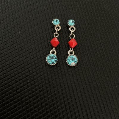 Sale Photo Thumbnail #147: Pair of costume dangle earrings featuring light blue round rhinestones and red bicone-style beads on silver-tone chain links. Note: One earring is missing its lower blue stone setting backing as shown in photos. Measures approximately 1.25 inches in total