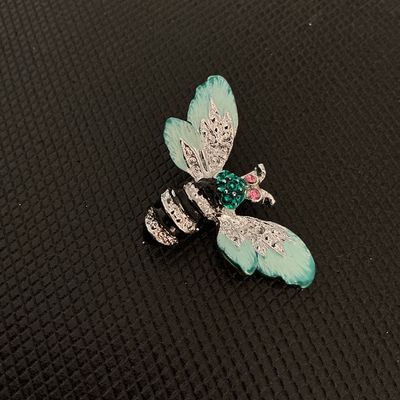 Sale Photo Thumbnail #217: A detailed bee brooch featuring silver-tone metal construction, light green enamel wing details, green rhinestones on the head, and pink rhinestone eyes. Black enamel striping decorates the body. Includes a standard pin back clasp mechanism. Appears in go