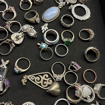 Sale Photo Thumbnail #120: Collection of sterling silver and costume jewelry, including various gemstone rings, pendants, and clip-on earrings displayed on a black tray.