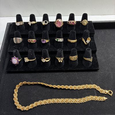 Sale Photo Thumbnail #116: Collection of vintage gold-tone rings with various gemstones displayed on cone stands, alongside a thick gold-tone rope chain necklace.