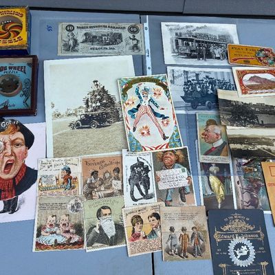 Sale Photo Thumbnail #69: Collection of antique ephemera including trade cards, vintage postcards, black-and-white photographs, scrip paper money, and small dexterity puzzle games from the late 19th to early 20th century.