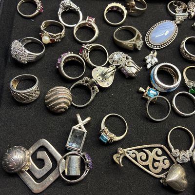 Sale Photo Thumbnail #119: Assortment of sterling silver and costume jewelry including gemstone rings, pendants, and clips displayed on a velvet tray.