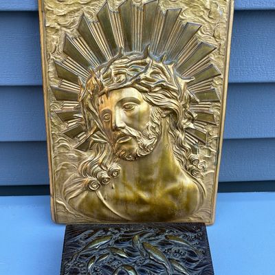 Sale Photo Thumbnail #65: Vintage brass plaque featuring a high-relief depiction of Jesus with a crown of thorns, displayed above a dark wooden trinket box with a carved aquatic fish lid.