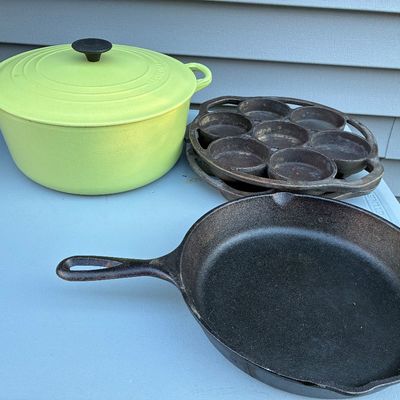 Sale Photo Thumbnail #113: Collection of cast iron cookware, including a bright green Le Creuset enameled Dutch oven, a Lodge skillet, and a vintage muffin/drop biscuit pan.