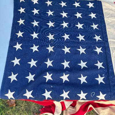Sale Photo Thumbnail #128: Vintage 48-star American flag canton featuring embroidered white stars on a blue field, laid over folded red and white stripes.