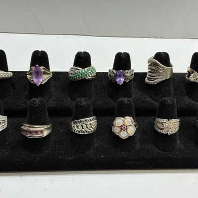 Sale Photo Thumbnail #117: Collection of twelve sterling silver statement rings displayed on a black velvet stand, featuring various gemstone accents including amethyst, emerald, turquoise, and mother-of-pearl.