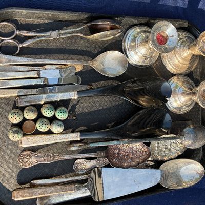 Sale Photo Thumbnail #5: Collection of silver-plated serving utensils and tableware, including a pie server, candleholders, salt shakers, and salad tongs on a black tray.
