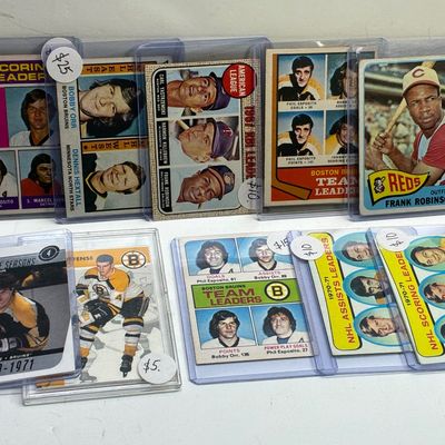 Sale Photo Thumbnail #90: Collection of vintage sports trading cards in protective plastic sleeves, including 1970s NHL and MLB players like Bobby Orr, Phil Esposito, and Frank Robinson.