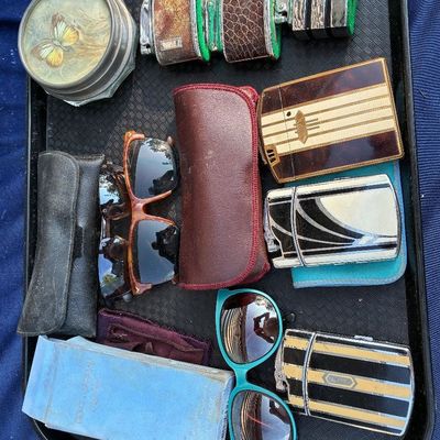 Sale Photo Thumbnail #26: Collection of vintage accessories on a tray, including Art Deco enamel cigarette lighters, sunglasses, leather eyewear cases, a Dolce & Gabbana perfume box, and a round butterfly trinket dish.