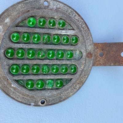 Sale Photo Thumbnail #66: Vintage Persons Cataphote green glass marble reflector signal light in a weathered cast metal housing, featuring patent pending markings.