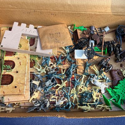Sale Photo Thumbnail #13: Vintage Marx Alamo playset in a cardboard box, including plastic figures, cannons, horses, accessories, and printed cardboard structure pieces.