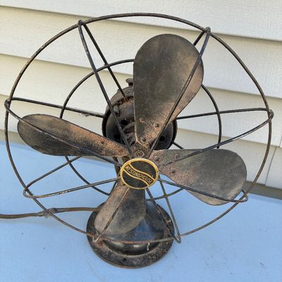 Sale Photo Thumbnail #127: Vintage Westinghouse four-blade electric desk fan with a metal cage guard, showing age-appropriate surface rust and patina.