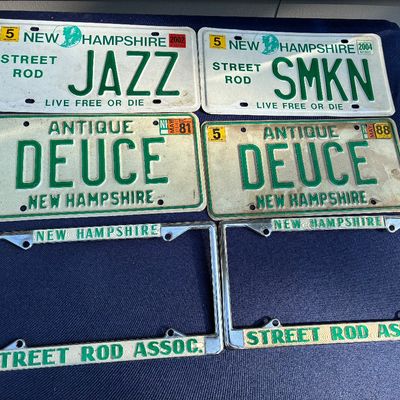 Sale Photo Thumbnail #21: Collection of four vintage New Hampshire specialty license plates, featuring custom vanity text including "JAZZ", "SMKN", and a matching pair of "DEUCE" antique plates, alongside two metal Street Rod Assoc. license plate frames.