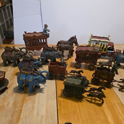 Sale Photo Thumbnail #54: Collection of vintage cast iron circus toys, including painted elephants, horse-drawn wagons, and animal cages.