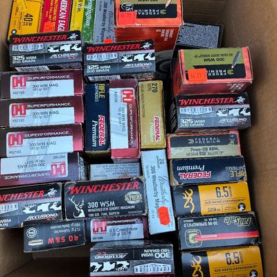 Sale Photo Thumbnail #55: Cardboard box filled with various brands and calibers of rifle and handgun ammunition, including Federal, Winchester, and Hornady.