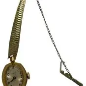 Vintage gold-tone women's wristwatch featuring an oval dial with Arabic numerals and a textured expansion band with a safety chain.