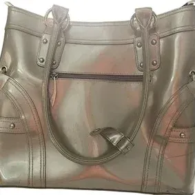 Metallic bronze or pewter patent leather handbag featuring shoulder straps, studded accents, and a front zippered pocket.