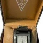 Vintage Guess quartz watch featuring a rectangular silver-tone case and a wide black leather cuff strap, housed in its original branded...
