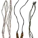 Trio of boho-style pendant necklaces, including a carved flower pendant on a seed bead strand, an intricate black circular pendant on a...