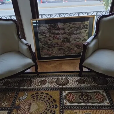Sale Photo Thumbnail #16: Pair of vintage French Provincial style armchairs with off-white upholstery and dark wood trim, set beside a large framed Asian art piece.