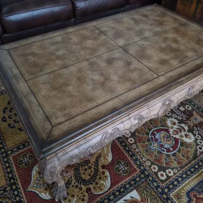 Sale Photo Thumbnail #19: Traditional French Provincial style coffee table with a four-panel leather inset top, carved apron, and claw feet.