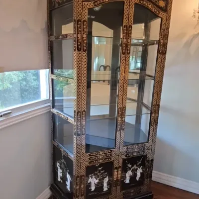 Sale Photo Thumbnail #8: Asian-style black lacquer display cabinet featuring ornate gold gilt detailing, mother-of-pearl figures on lower cabinet doors, glass side panels, and interior shelves.