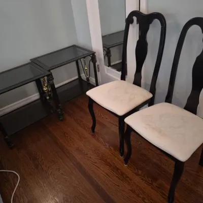 Sale Photo Thumbnail #38: Pair of black-lacquered Queen Anne style side chairs with cream upholstered seats, alongside two matching dark wood glass-top end tables.