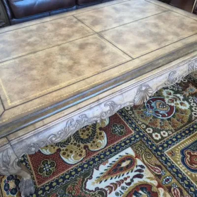 Sale Photo Thumbnail #48: Traditional carved wood coffee table with gold-tooled faux leather inset panels and claw foot legs.