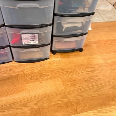 Set of black plastic storage carts with clear frosted drawers, sitting on light hardwood flooring.