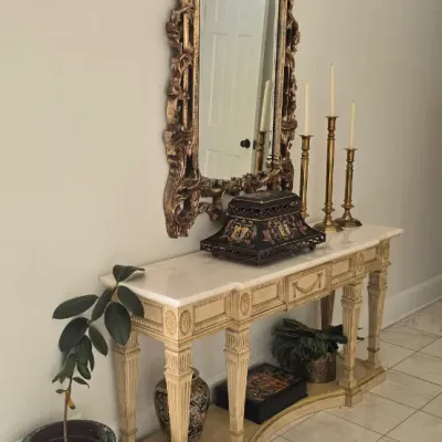 Sale Photo Thumbnail #3: French Neoclassical-style marble-top console table paired with an ornate gilded wall mirror and brass candlesticks.